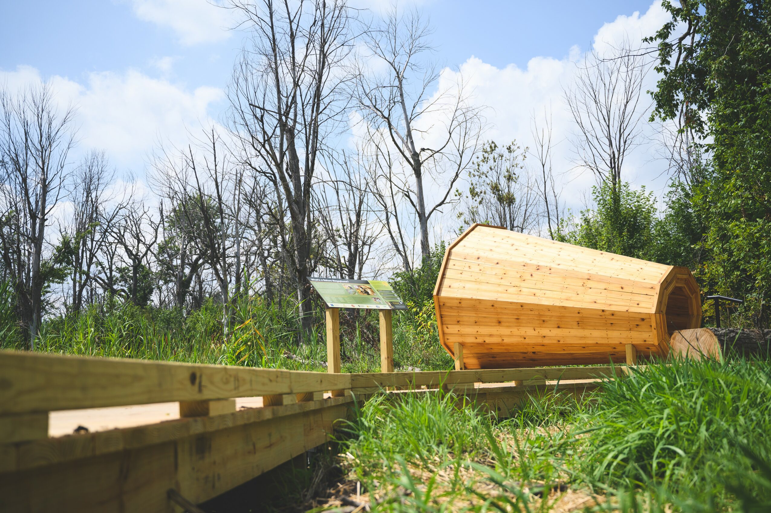 Wooden structure on a grassy area with trees and blue sky in the background.