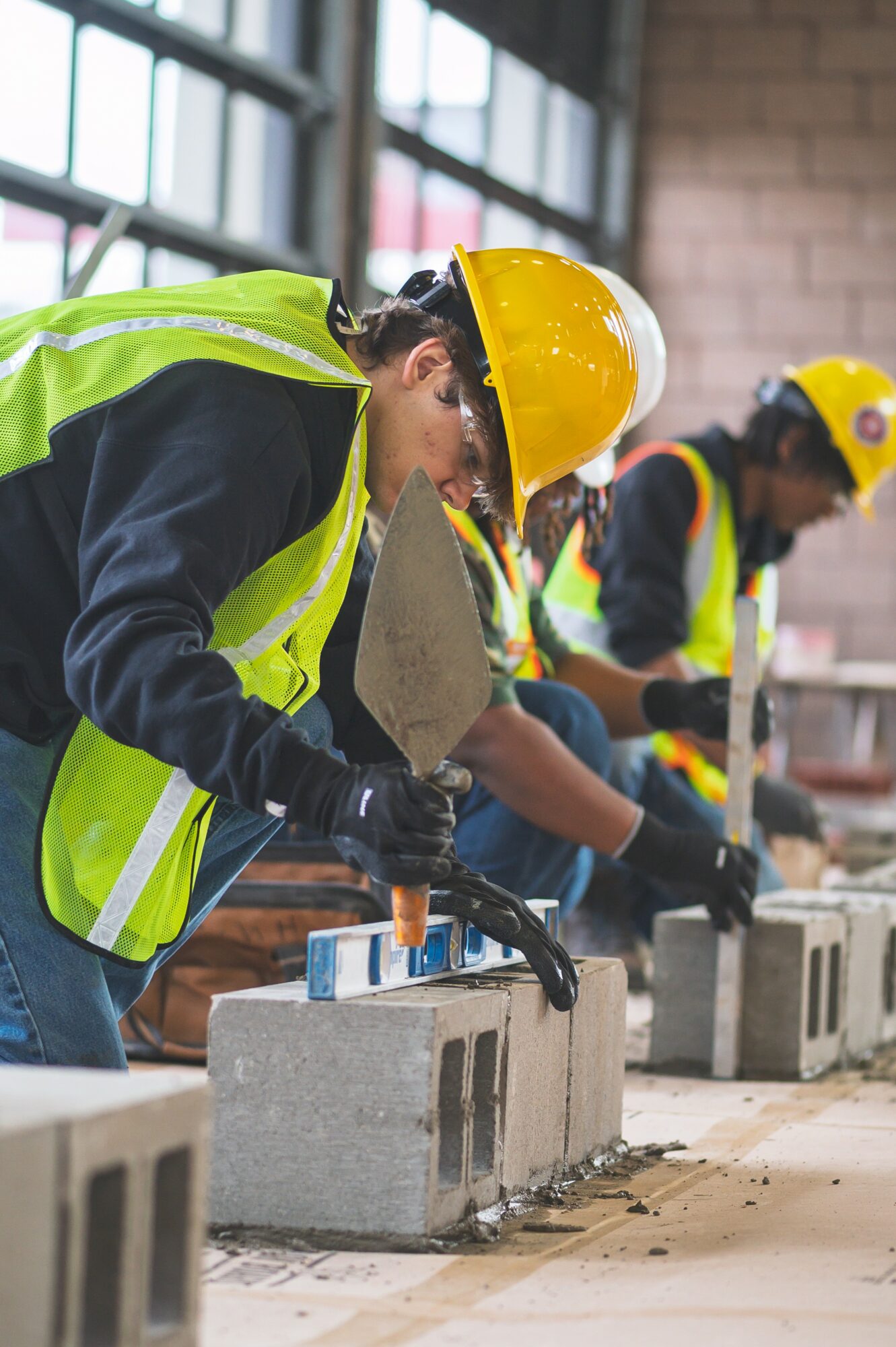 Worker in safety gear and helmet inspects concrete blocks in a construction site.