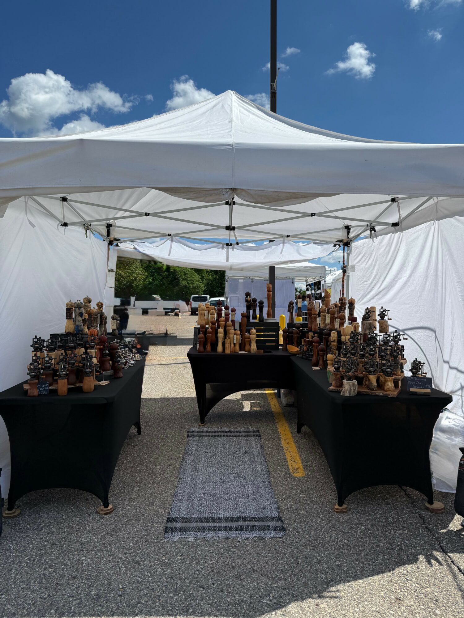 Display of chess sets under a white canopy tent outdoors on a sunny day.