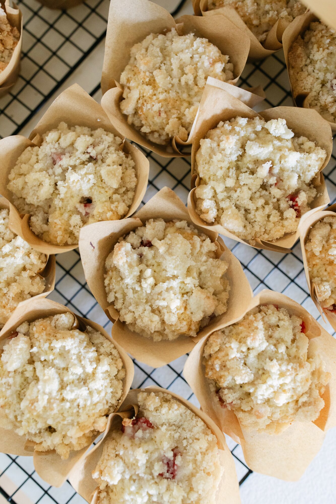 Several crumbly muffins in paper liners on a wire cooling rack, some with visible fruit pieces.
