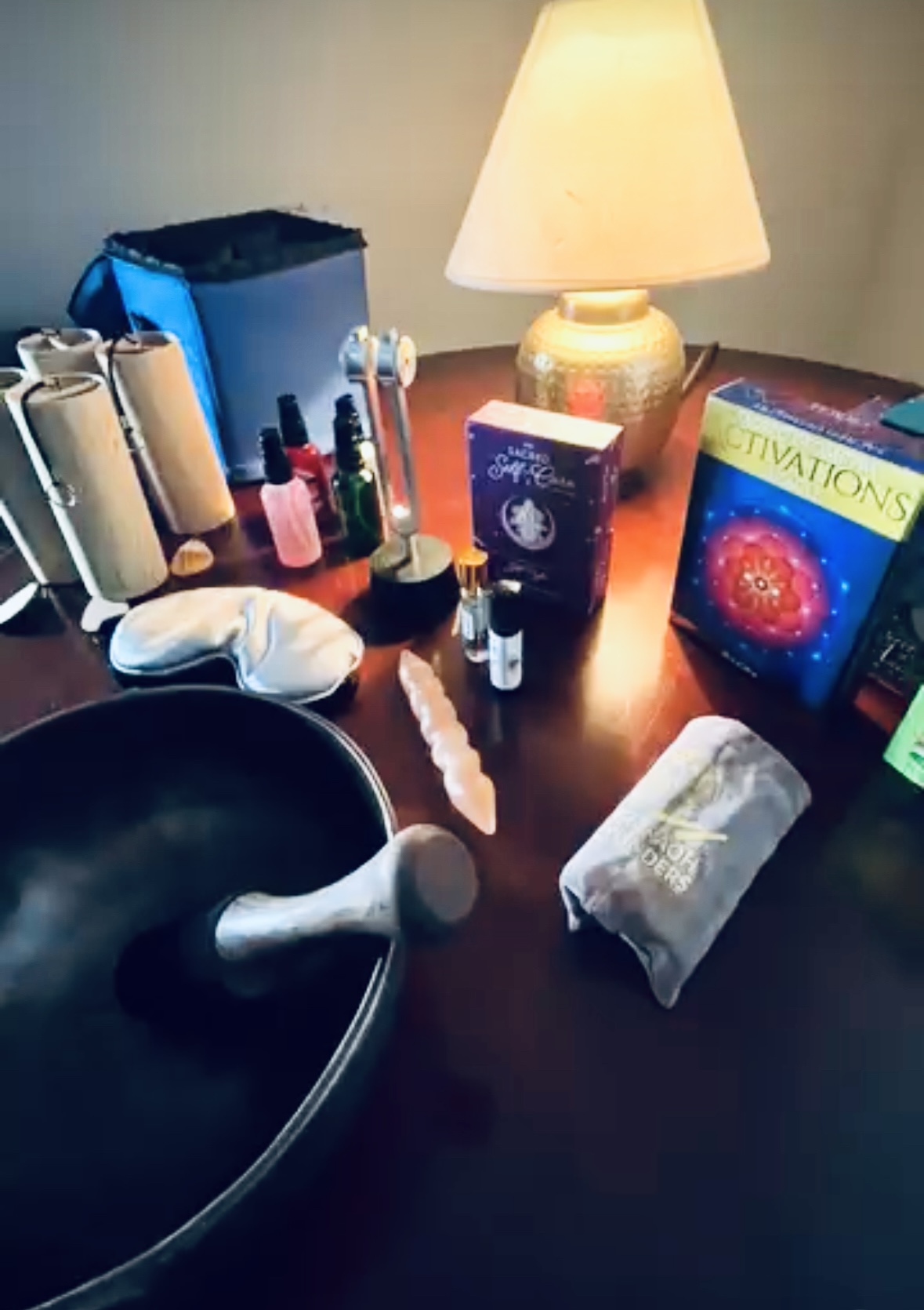 Nail polish bottles, a lamp, a box, a towel, and a bowl on a wooden table.