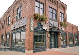 Corner brick building with large windows, decorative metalwork, and hanging plants, numbered 336, on a city street.