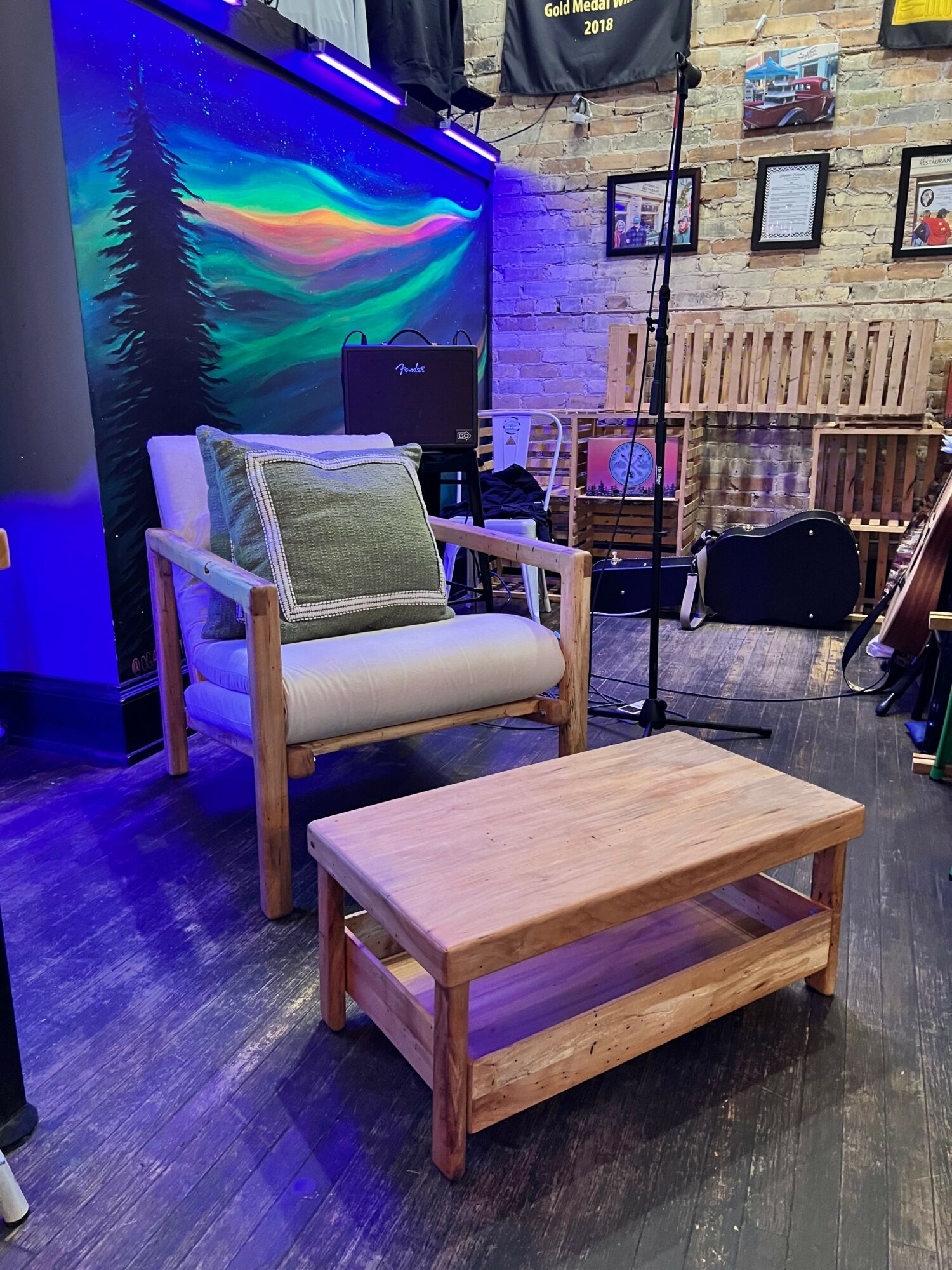 Wooden chair with a cushion and a small wooden table in a room with a colorful wall display.