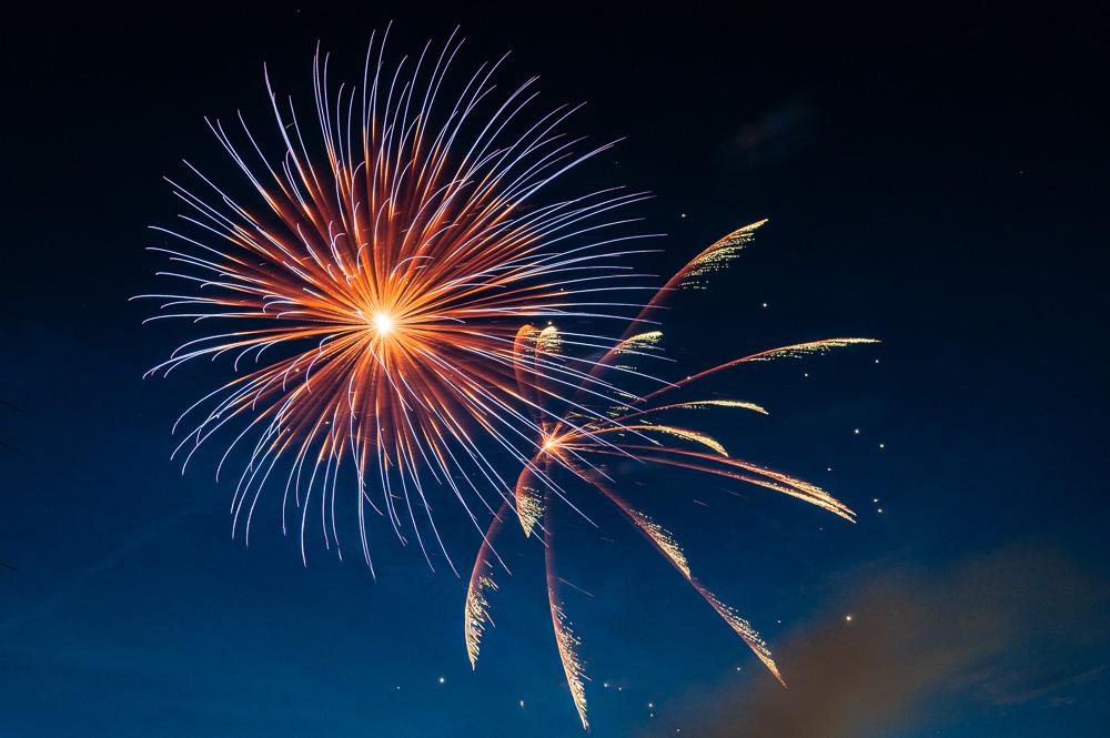 Fireworks exploding in the night sky with colorful streaks radiating outward.