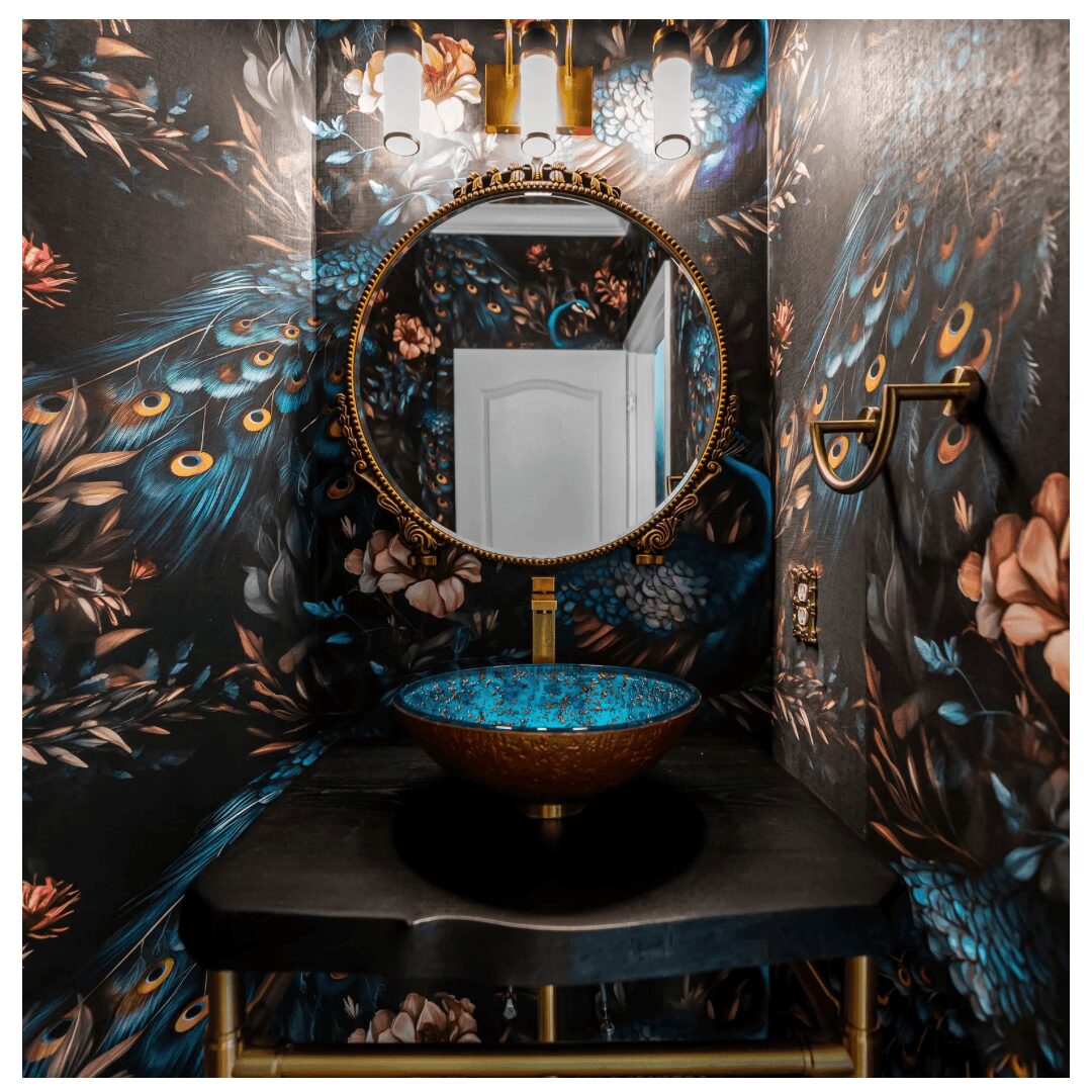 Decorative bathroom with peacock feather wallpaper, round mirror, ornate sink, and gold fixtures.