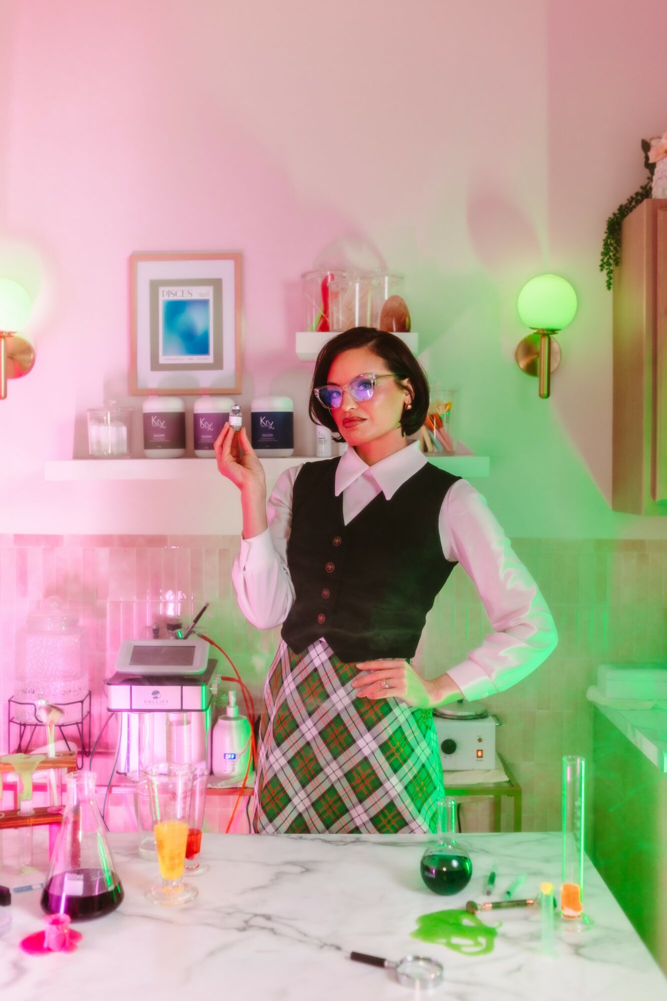 Woman with glasses holding a phone in a colorful, decorated room with pink and green lighting, a marble table, and various objects.