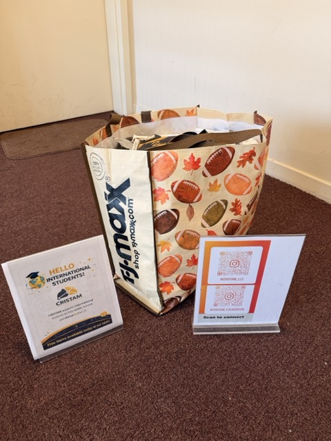 A paper bag with a fall-themed design, two signs with text, and a brown carpeted floor.