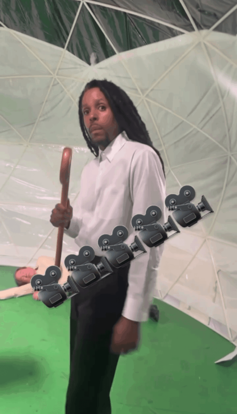 Person holding a mop and a skateboard, standing in front of a large umbrella-like structure.