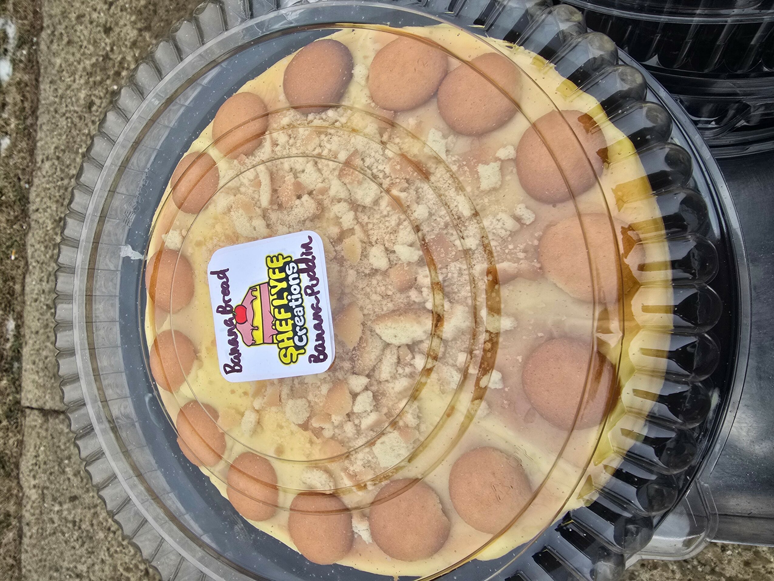 Round pizza with cheese and pepperoni slices in a clear plastic container, viewed from above.