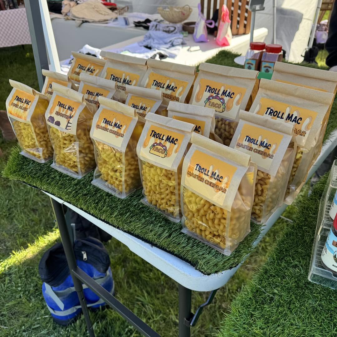 Multiple bags of popcorn labeled 'Troll Mac' arranged on a table outdoors, with a grassy background.