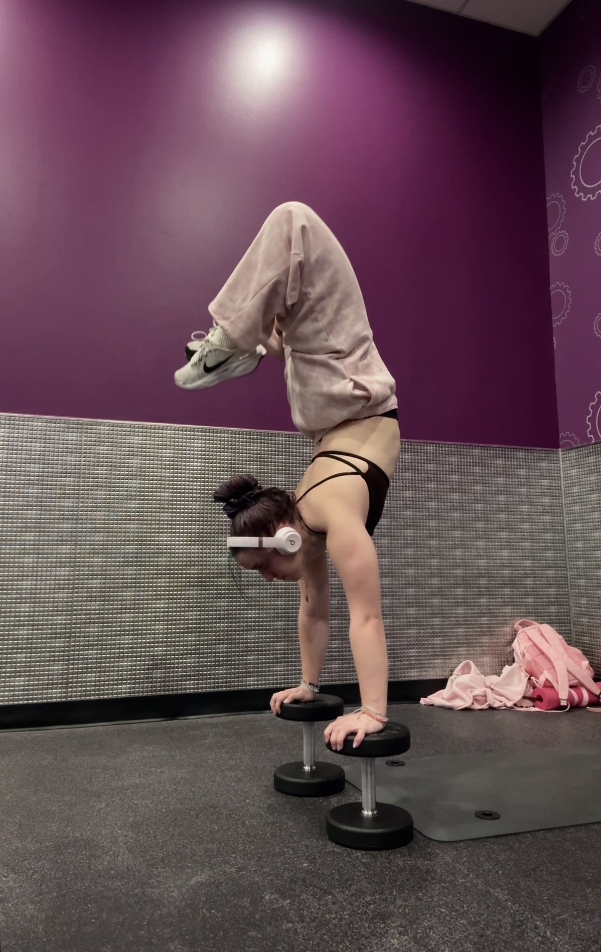 Person performing a handstand on small exercise steps in a gym with purple and gray walls.