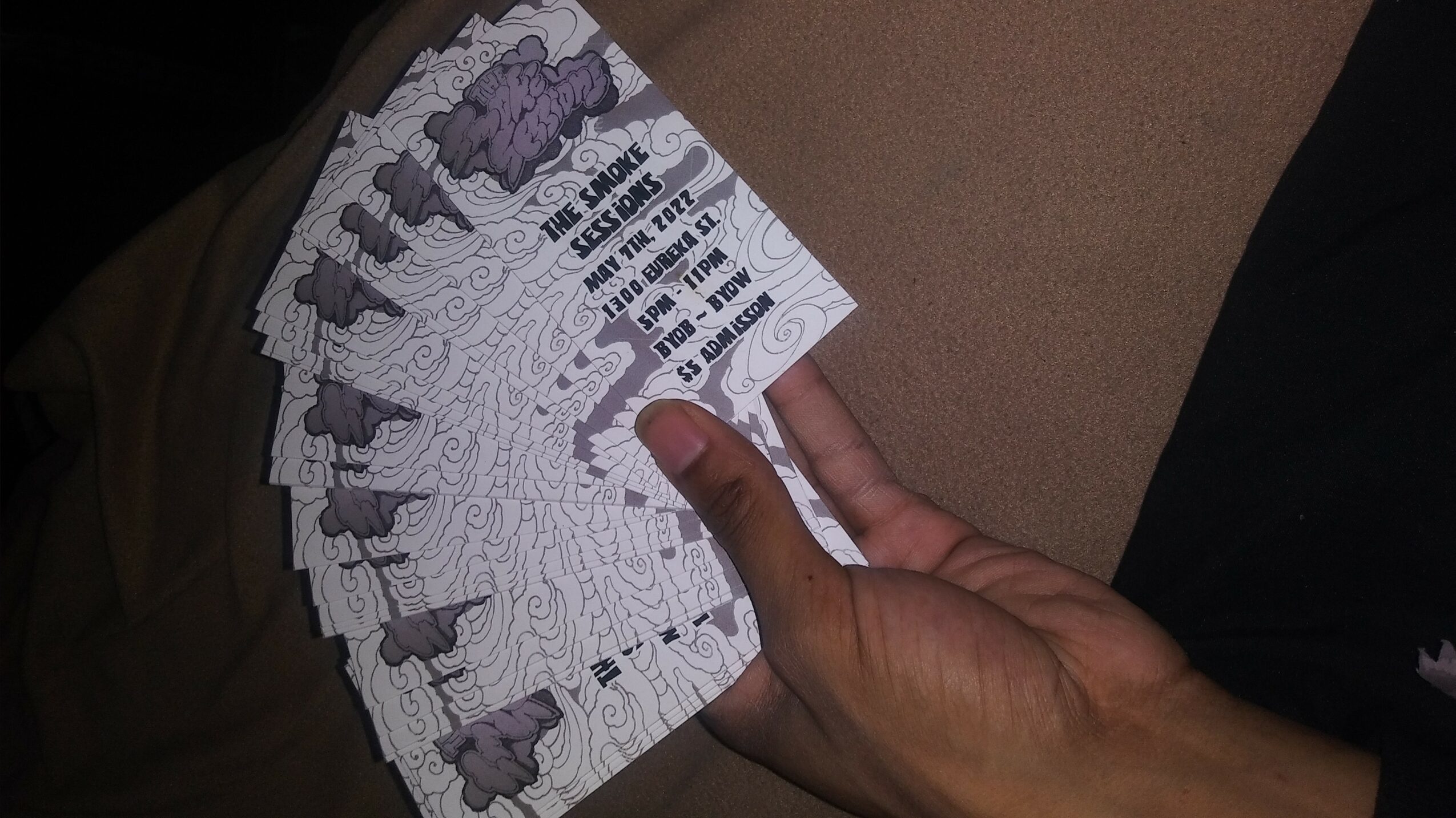 Person holding multiple tickets or coupons with printed text and images, fanned out in hand.