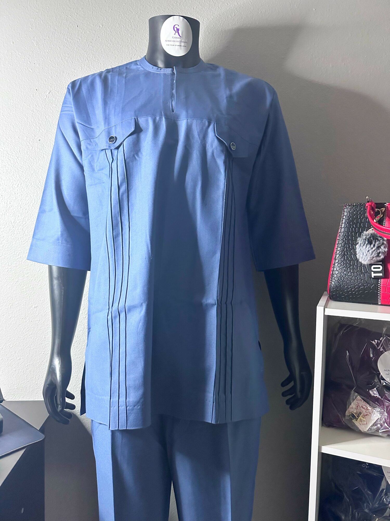 Mannequin wearing a blue tunic and matching pants, standing indoors with a white wall background.