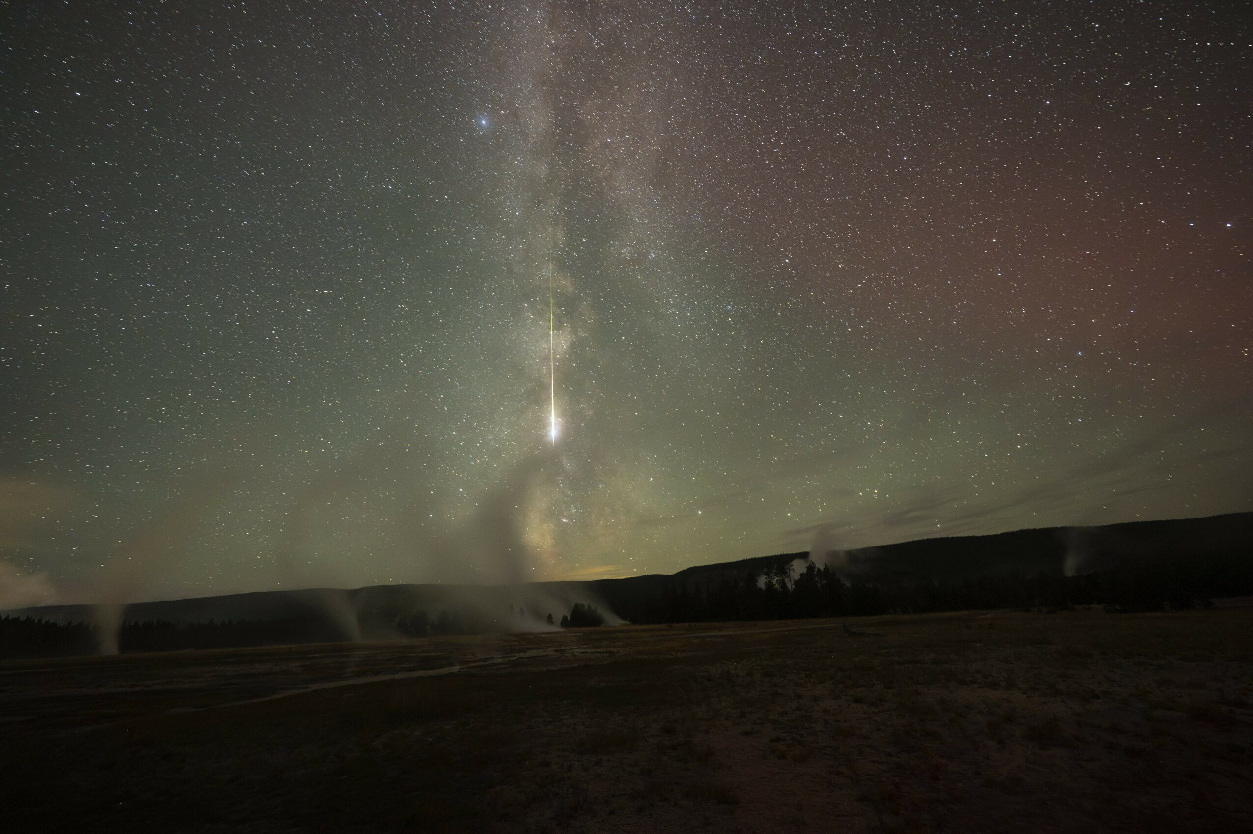 Night sky with the Milky Way galaxy visible above a landscape, stars scattered across the sky.
