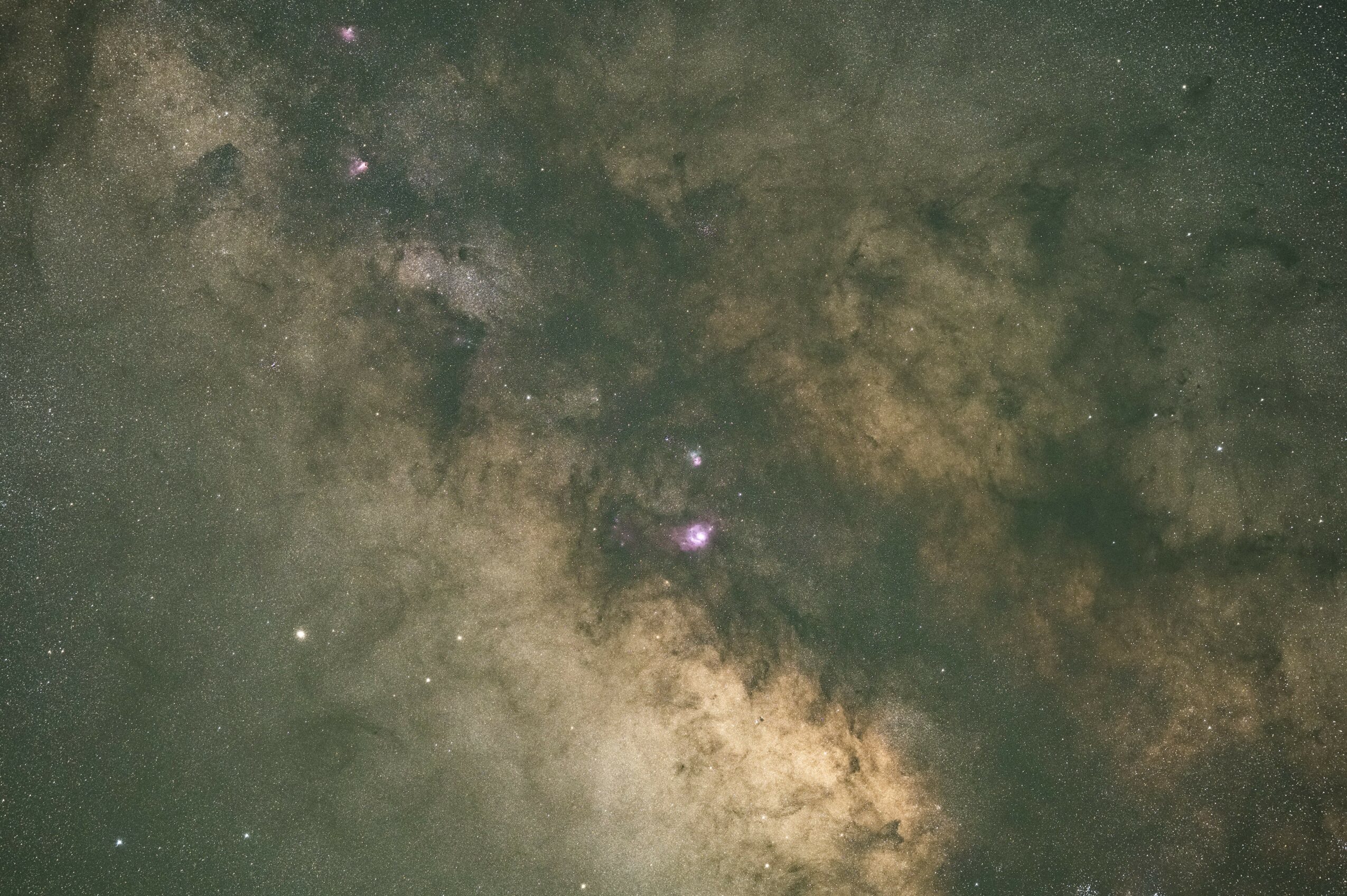 Night sky with stars and the Milky Way galaxy visible, with a cloudy appearance and various bright points of light.