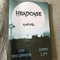 Book cover titled 'Headcase' with a landscape scene, windmill, and power lines, featuring author names Ken MacGregor and Kerry Lapp.