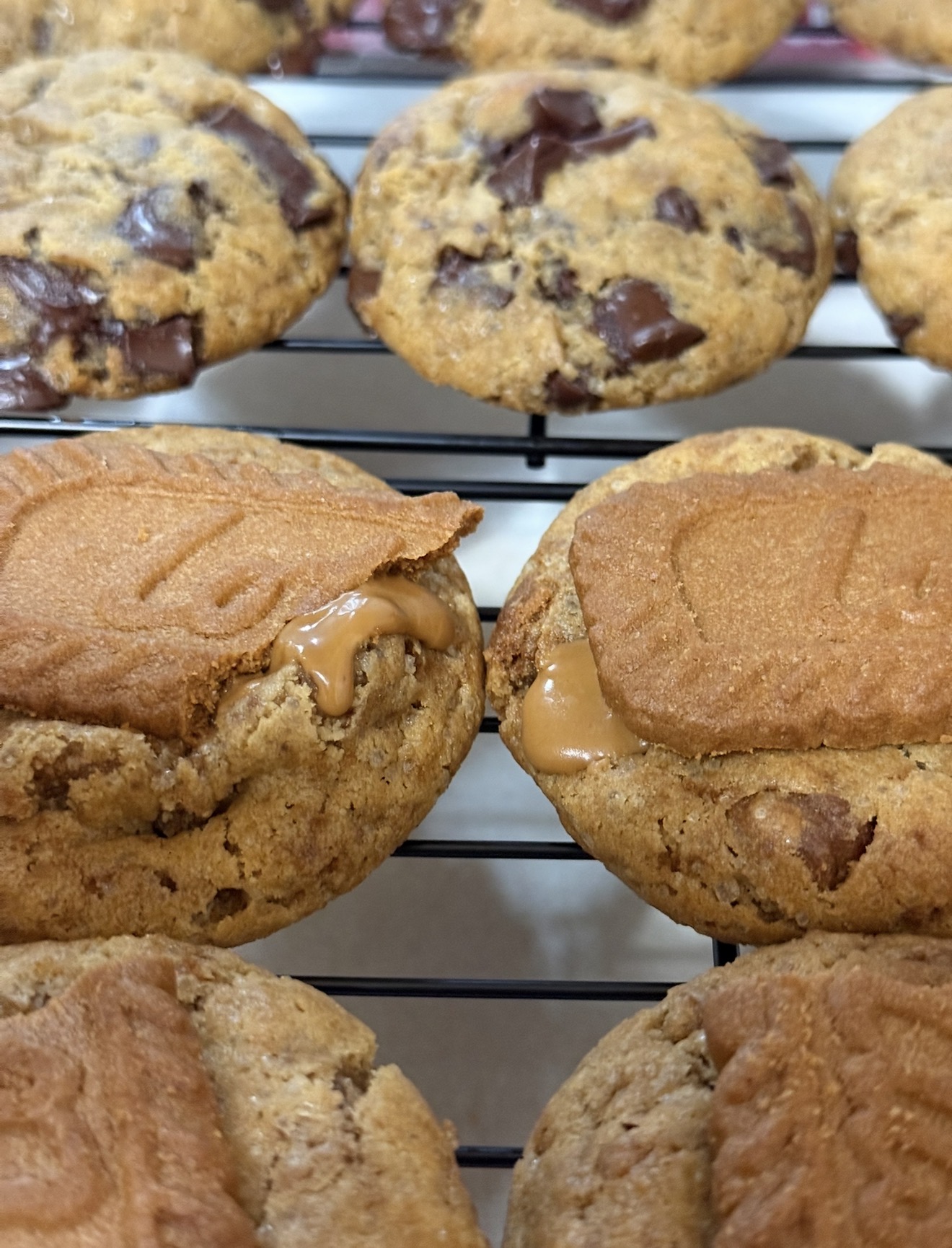 Chocolate chip cookies with peanut butter filling on a cooling rack.