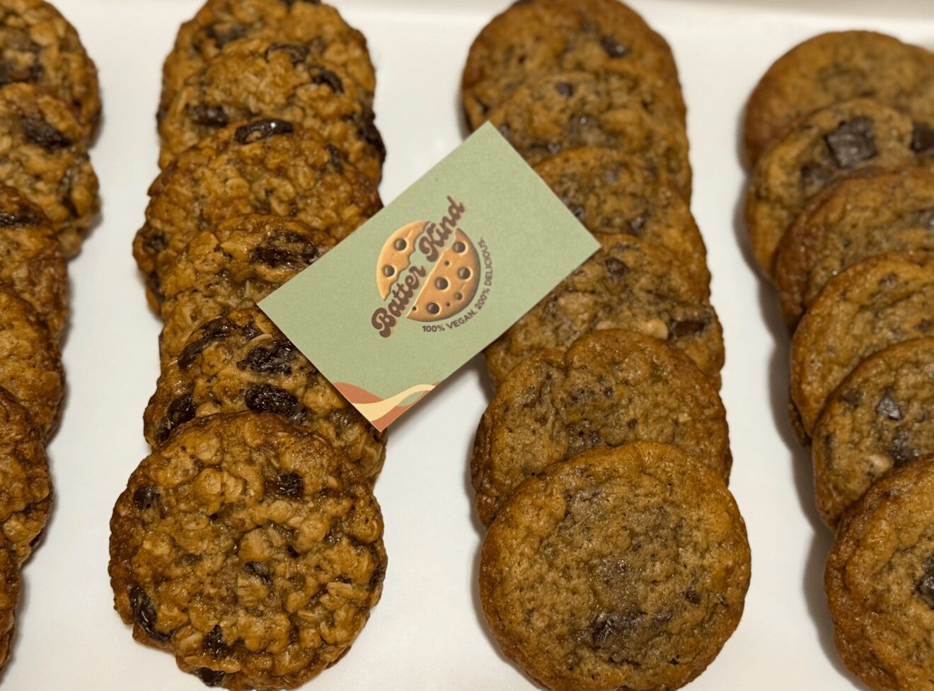Oatmeal raisin cookies arranged in rows with a small card in the middle, on a white surface.