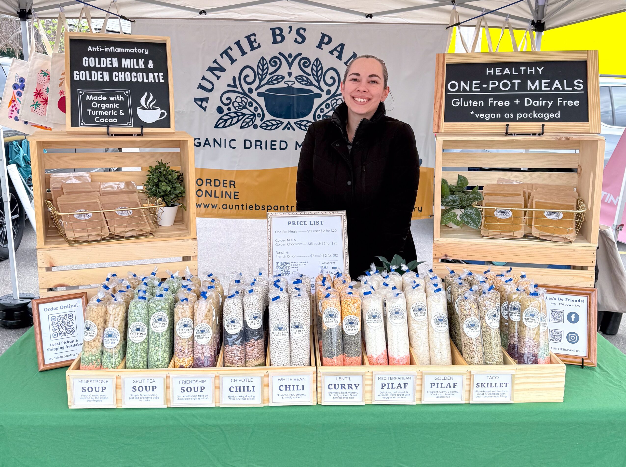 Woman standing behind a table with packaged dried foods at a market stall, banners display product information.