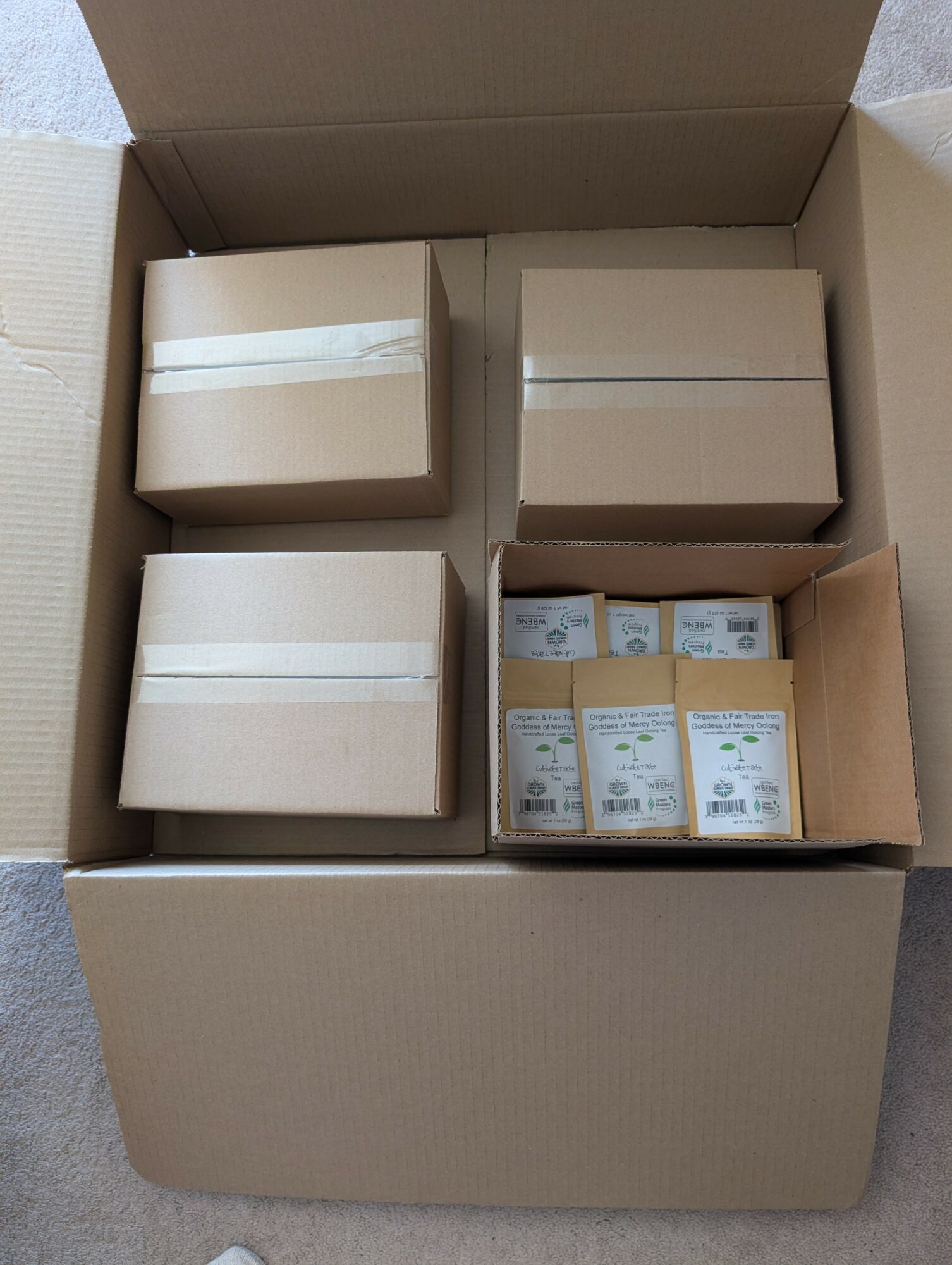 Open cardboard box containing four smaller boxes and three packages of medication or similar items, neatly arranged.
