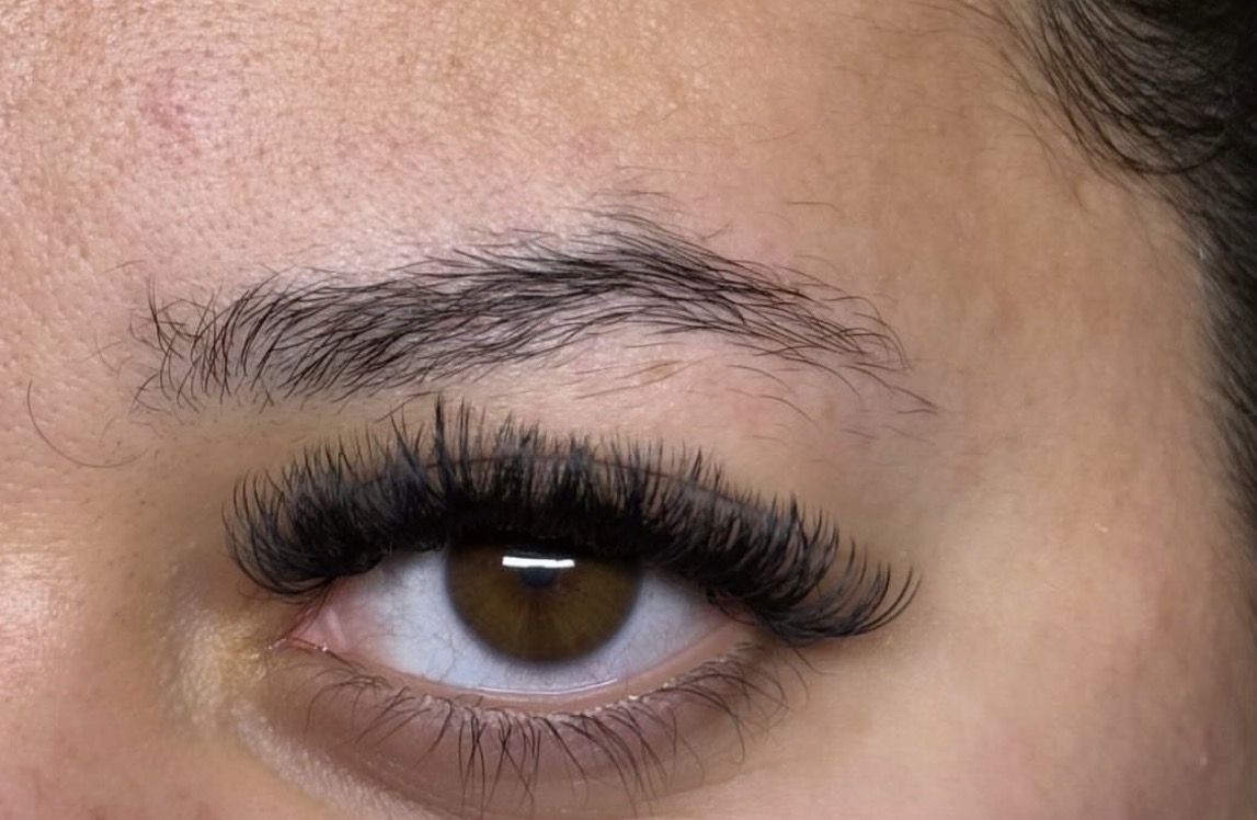 Close-up of a person's eye with long eyelashes and well-groomed eyebrow.