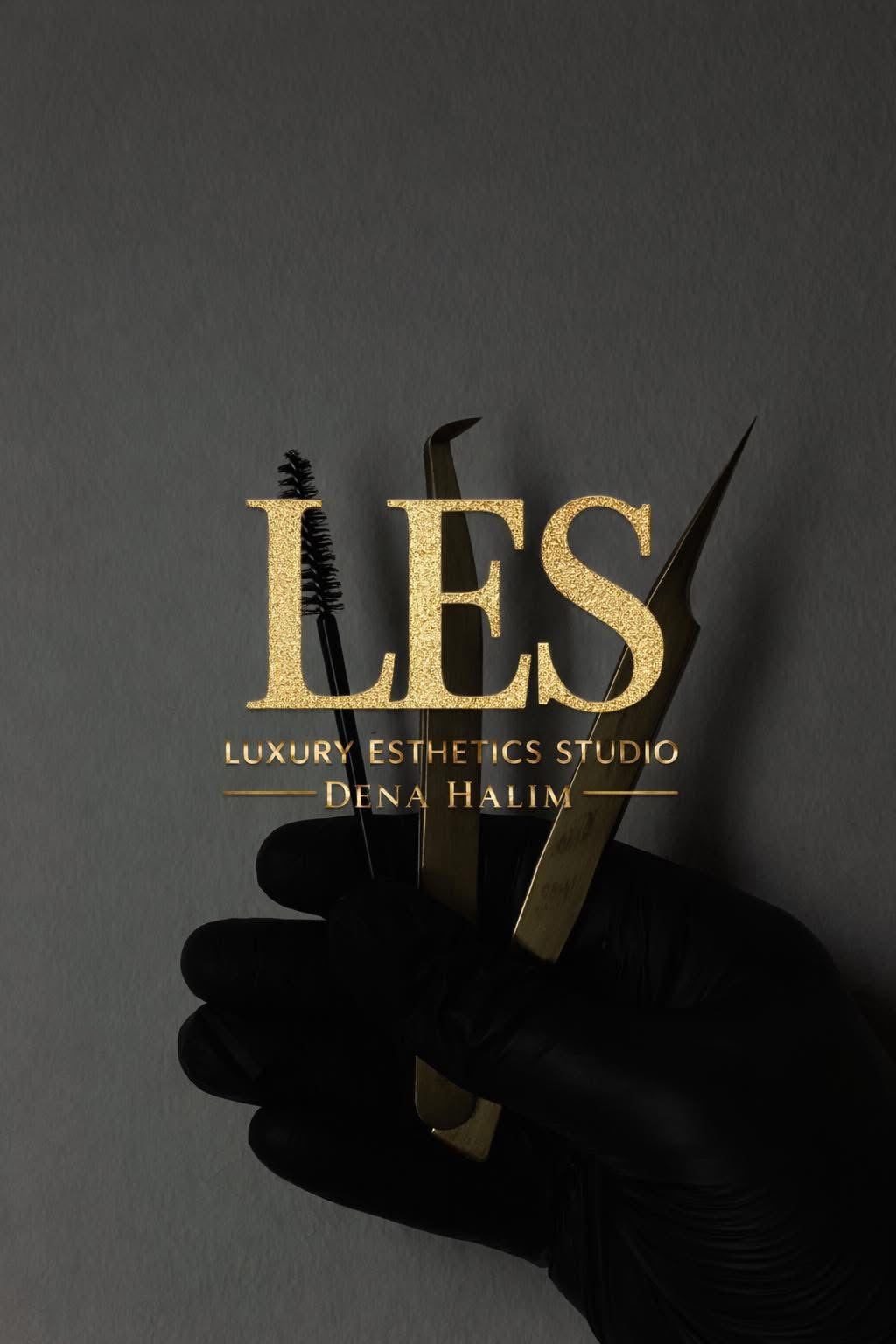 Black-gloved hand holding a gold pair of scissors against a dark background, with text overlay about a luxury esthetics studio.
