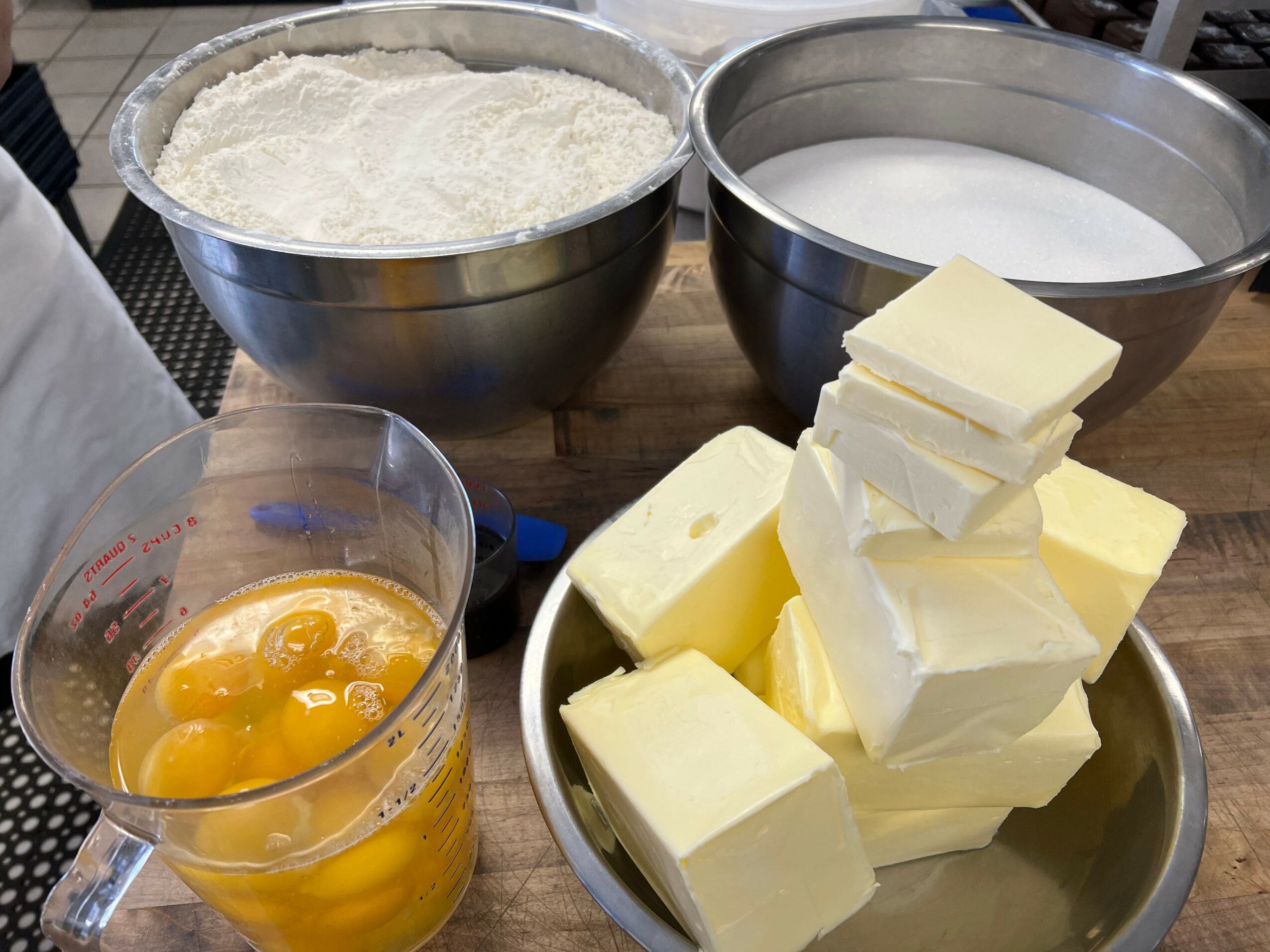 Baking ingredients including flour, butter, eggs, and milk on a wooden surface.