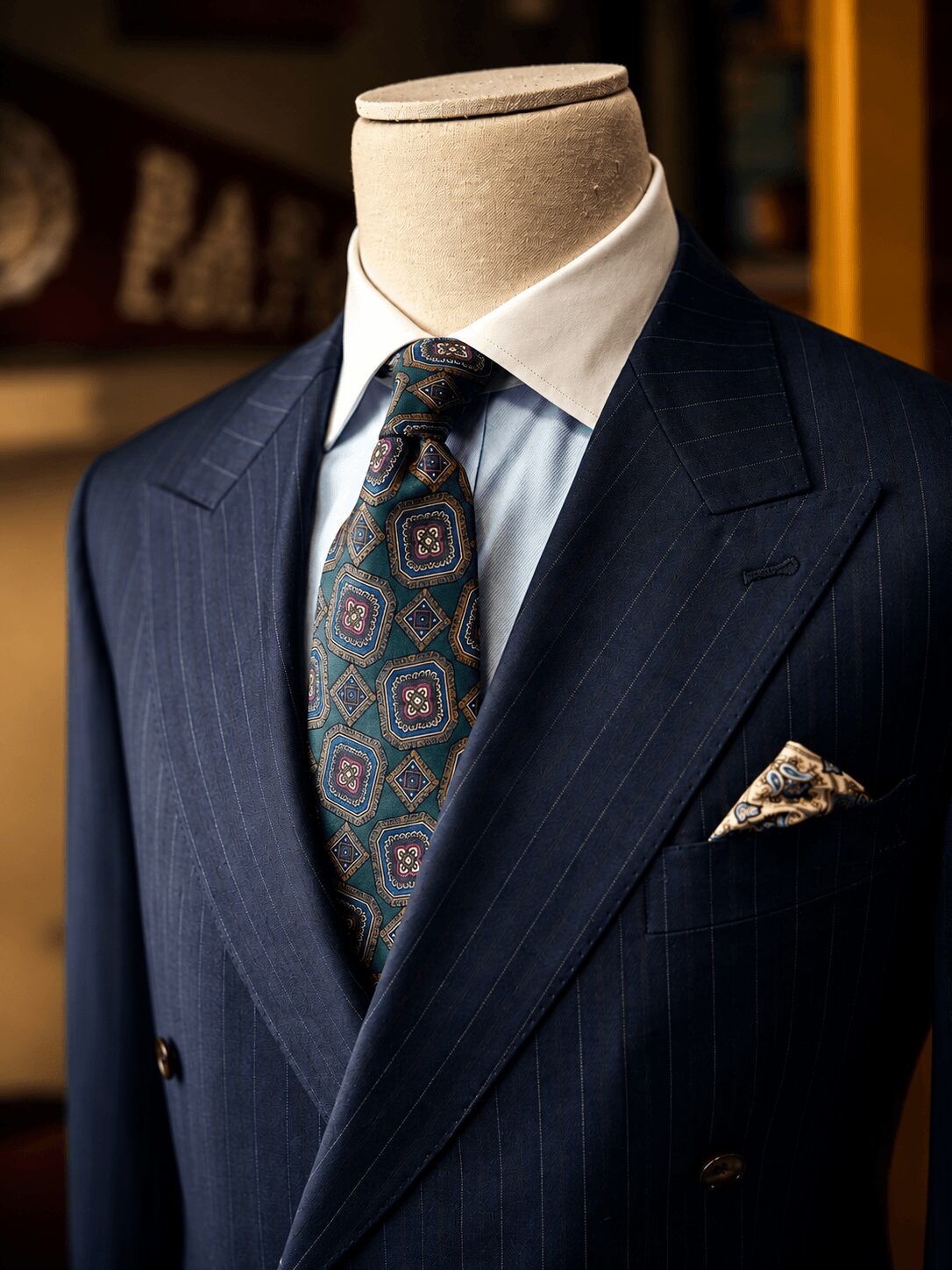 Mannequin dressed in a dark pinstripe suit, white shirt, patterned tie, and pocket square.