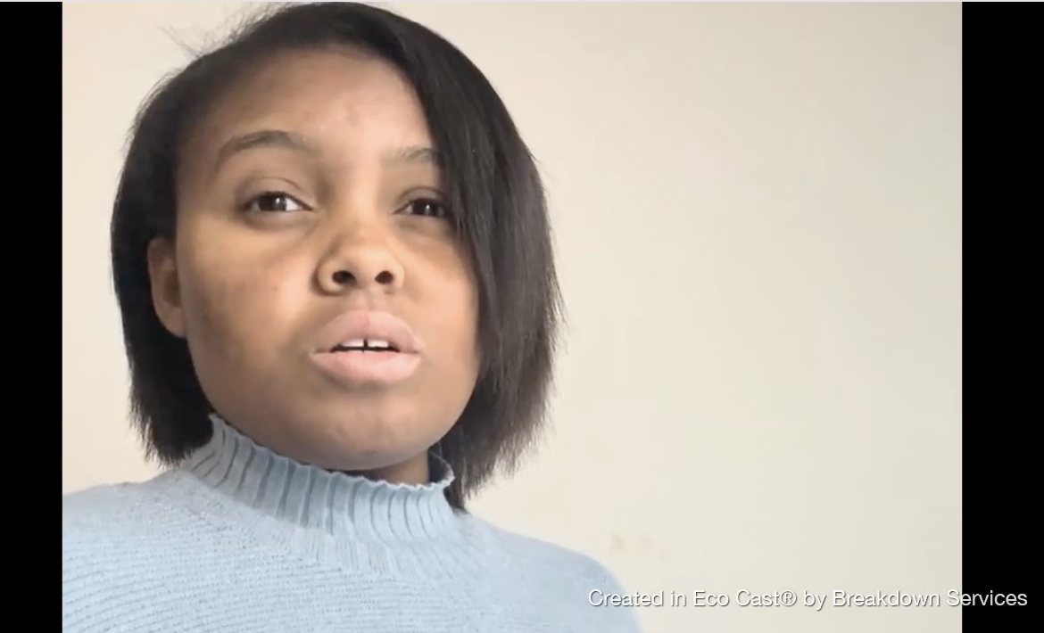 A woman with shoulder-length black hair wearing a light blue sweater looks at the camera with a neutral expression.