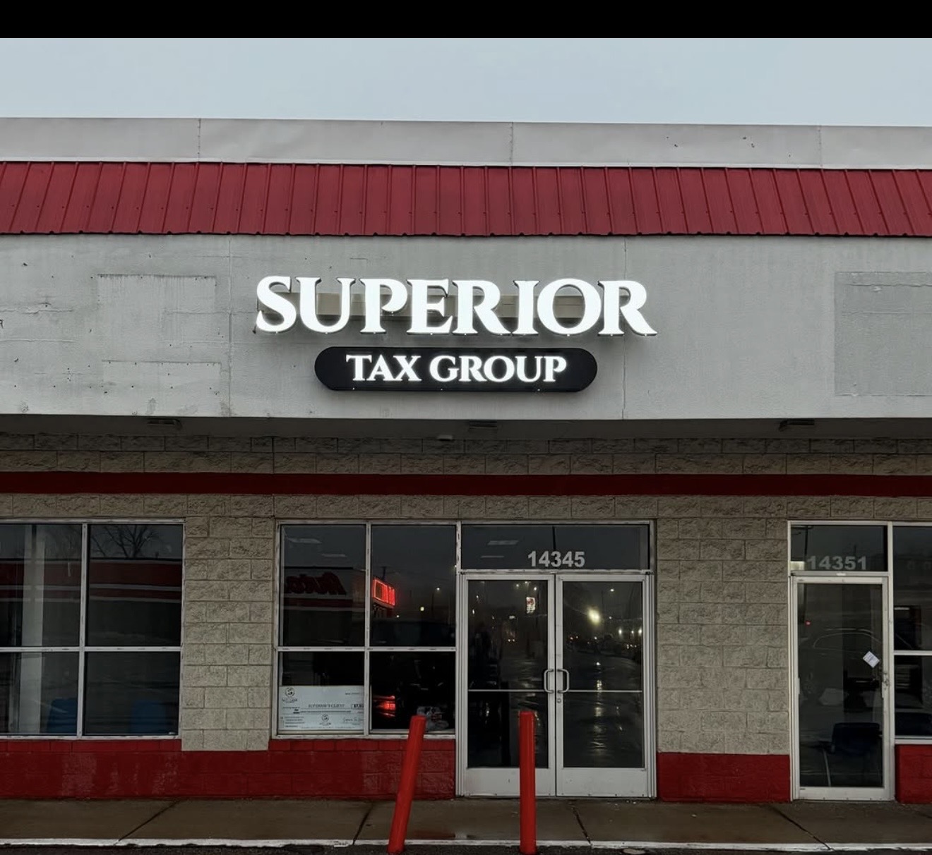 Storefront with sign reading 'SUPERIOR TAX GROUP' above entrance, building has large windows and a red and gray exterior.