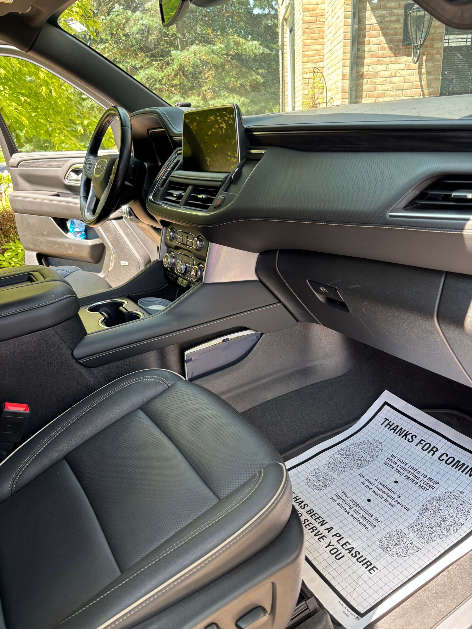 View of a car interior showing the driver's seat, dashboard, and a paper on the passenger side floor.