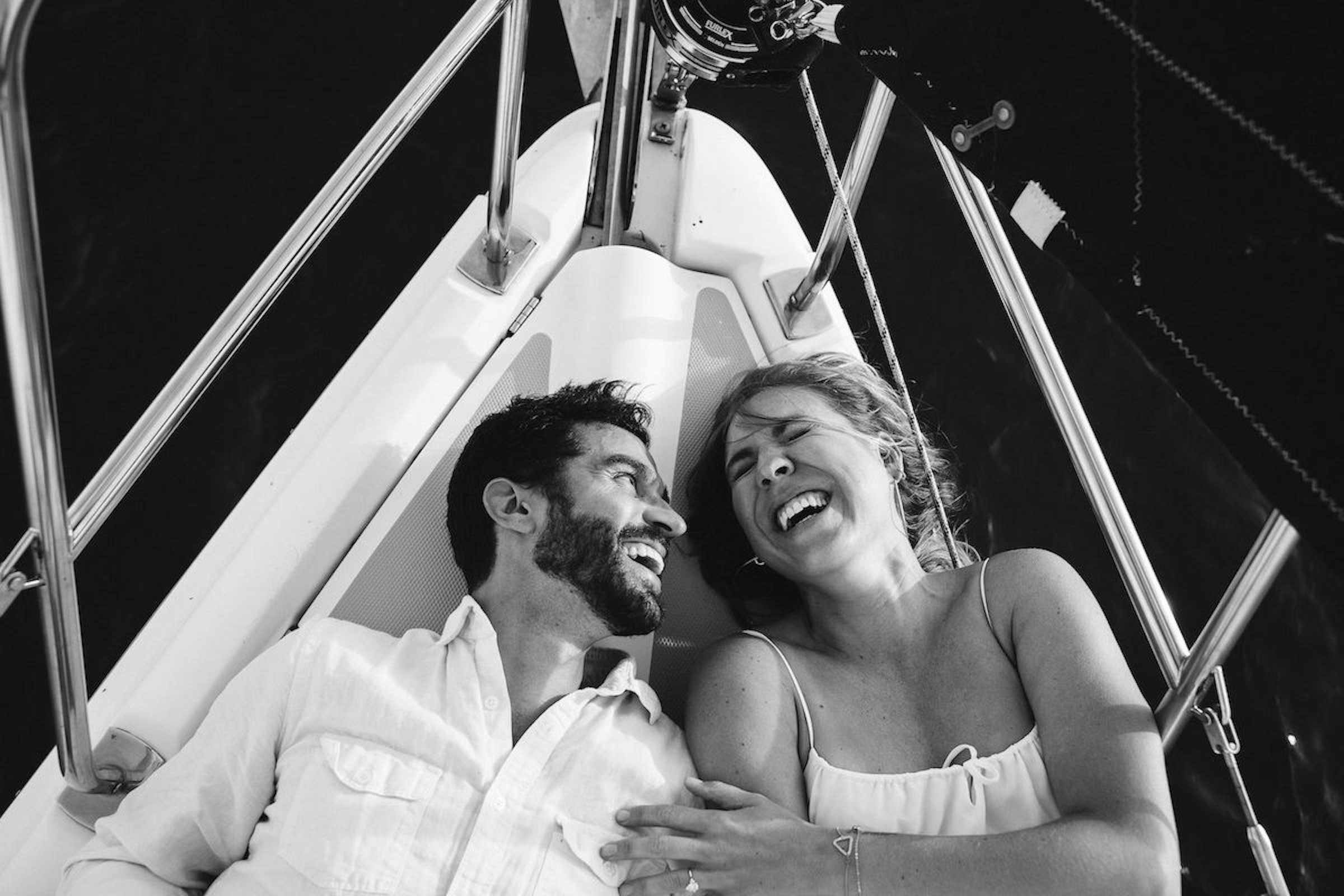 Two people lying on a swing, smiling and looking at each other, with metal support structures around them.