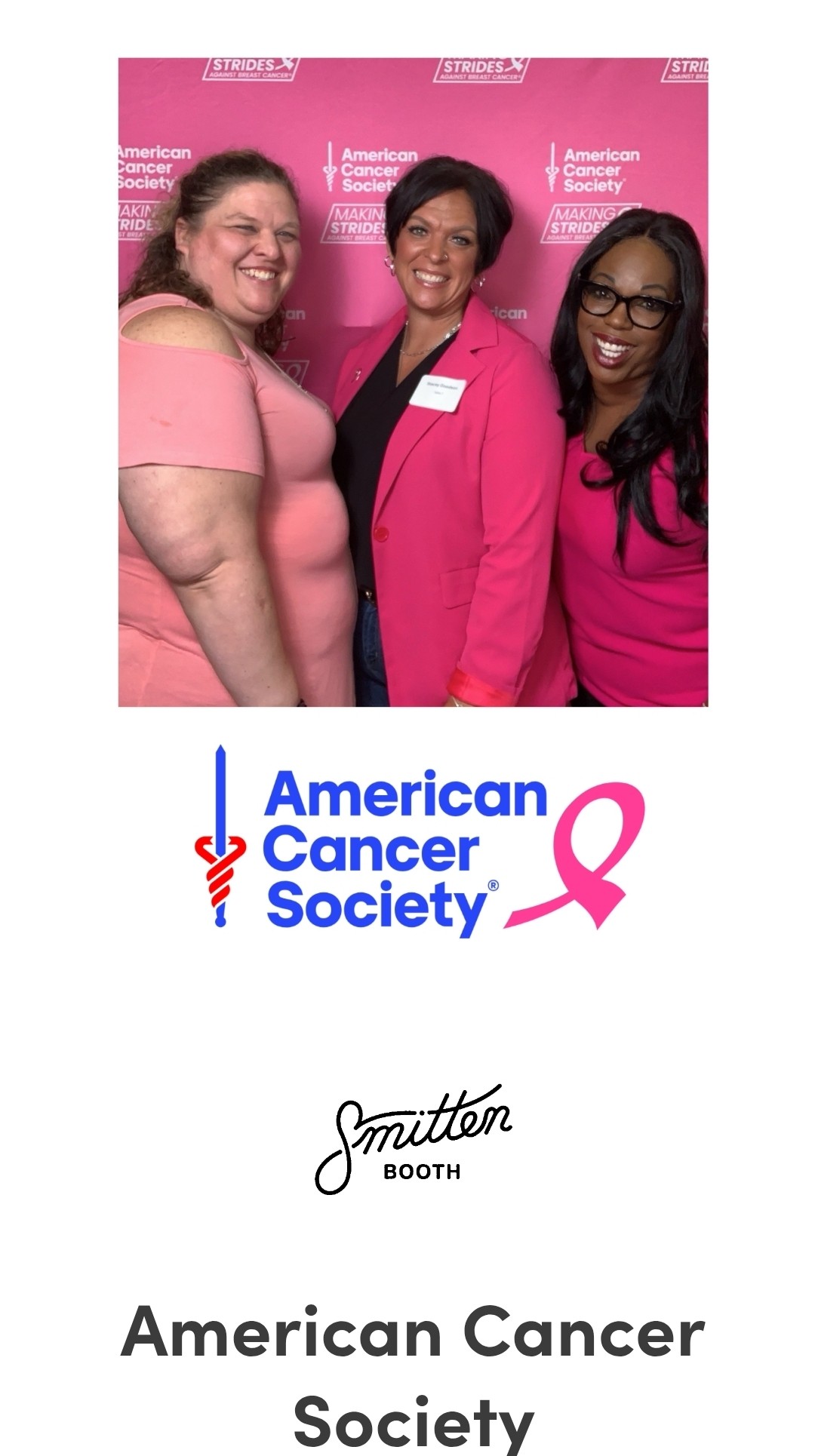 Three women smiling in front of a pink background with American Cancer Society logo and pink ribbon, wearing pink clothing.