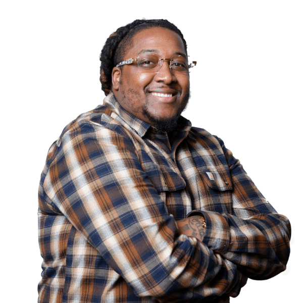 Person with glasses smiling, wearing a plaid shirt, arms crossed, against a white background.