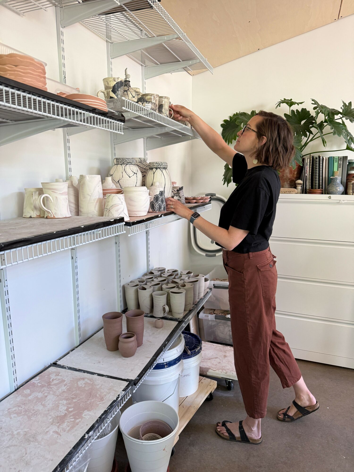 Person reaching into a refrigerated display case with bottles and containers inside, in a store or cafe setting.