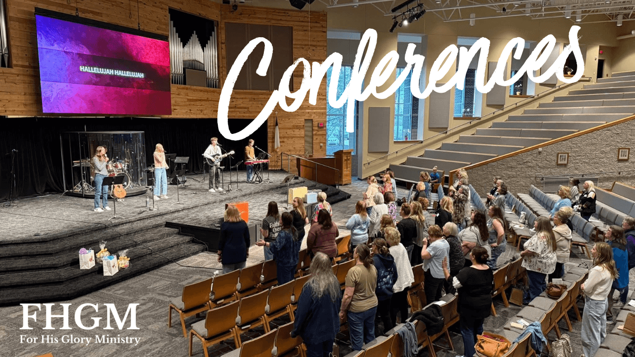 People gathered in a large conference hall with a stage, large screen, and seating area, attending a conference or event.