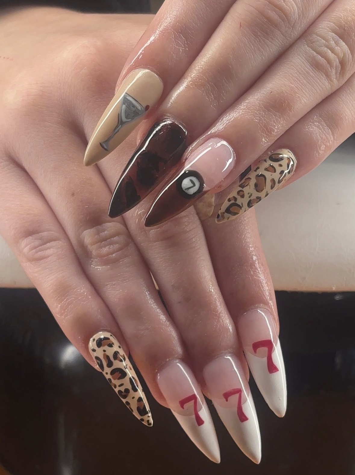 Close-up of hands with long, decorated nails featuring animal print, red accents, and various colors and designs.