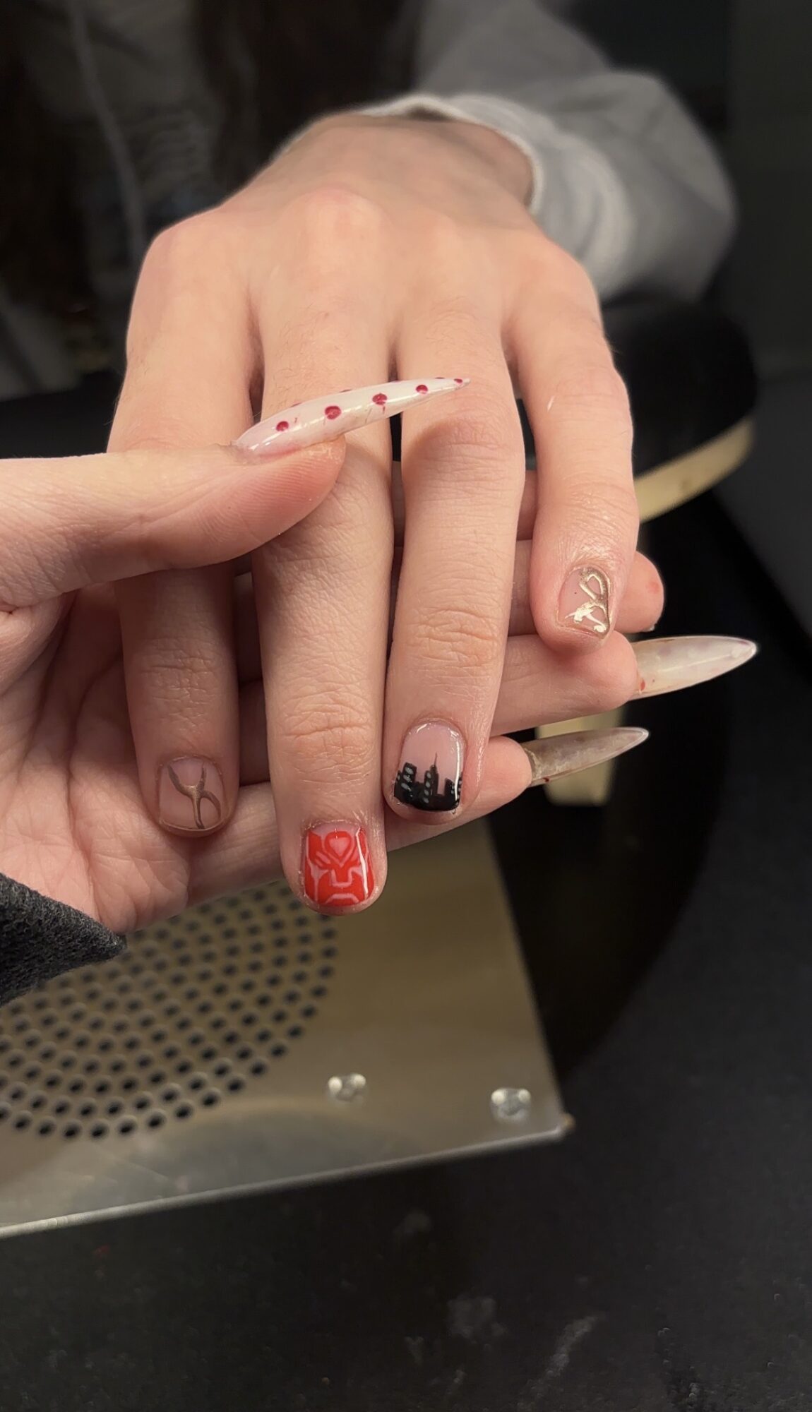 Close-up of hands with decorated nails, one hand resting on the other, background blurred.