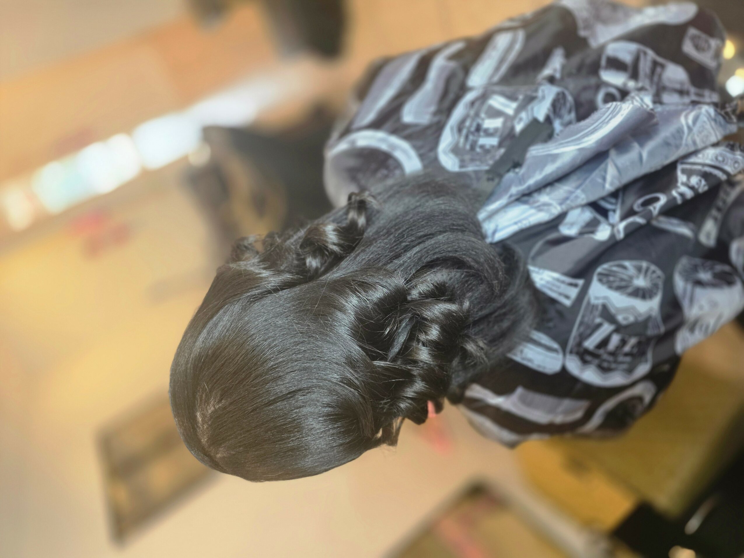 Top view of a person with dark, styled hair, wearing a patterned black and gray jacket.