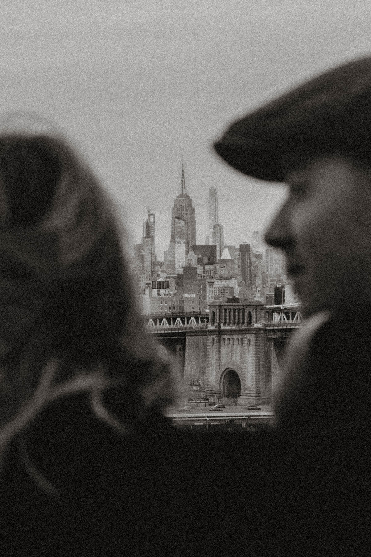 Two people in profile with a city skyline featuring a tall building in the background.