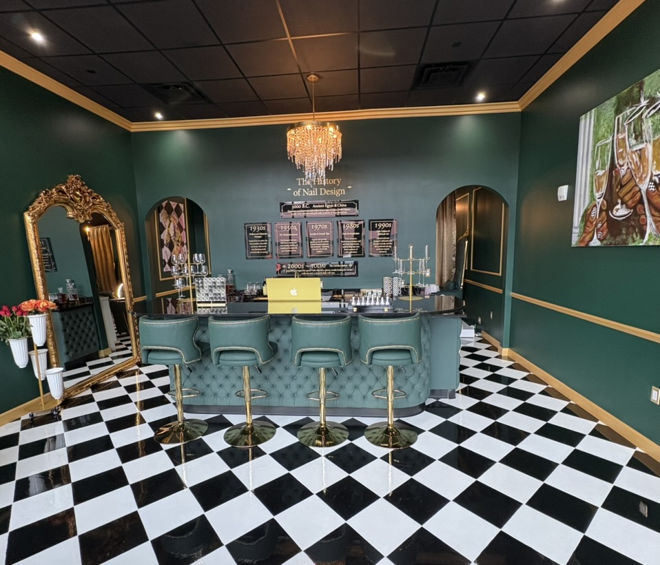 Elegant room with a bar, green walls, black and white checkered floor, gold accents, and a chandelier.