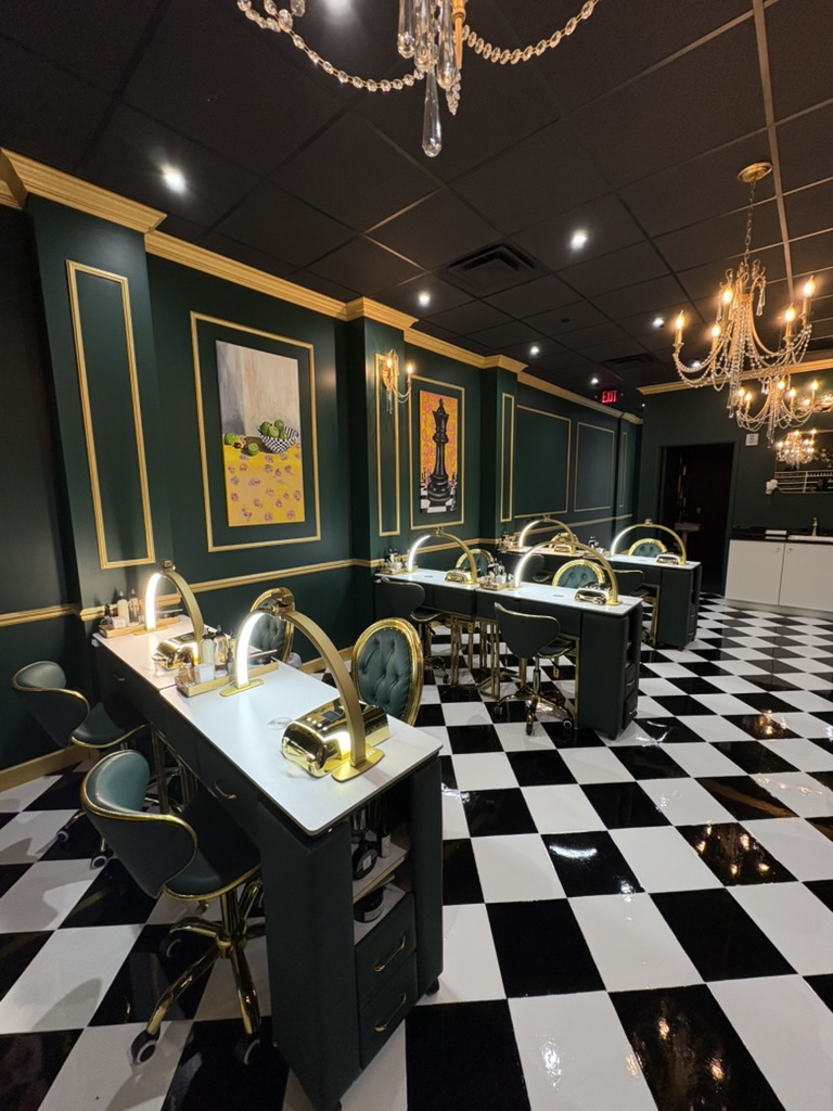 Elegant room with dark green walls, chandeliers, black and white checkered floor, and tables with gold lamps and chairs.