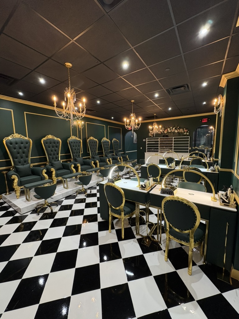 Elegant room with black and white checkered floor, green walls, gold accents, chandeliers, and chairs arranged along walls and tables.