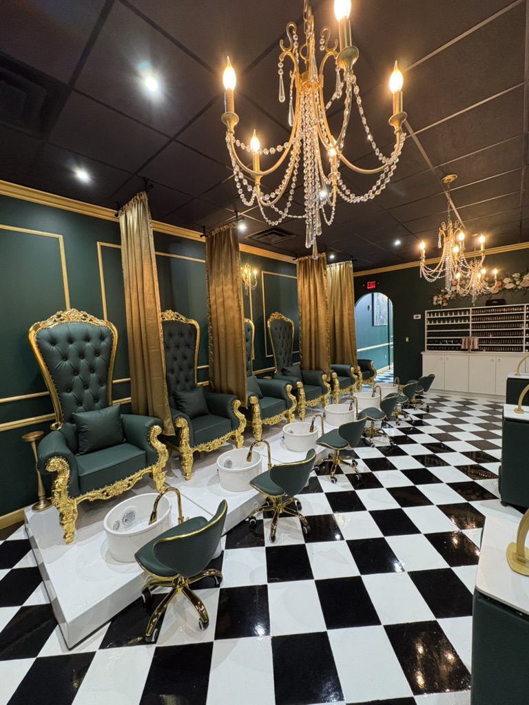 Luxurious room with high-backed teal chairs, gold accents, chandeliers, black and white checkered floor, and gold curtains.