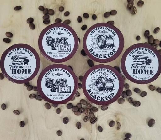 Four coffee cup labels with coffee beans scattered around on a light surface.
