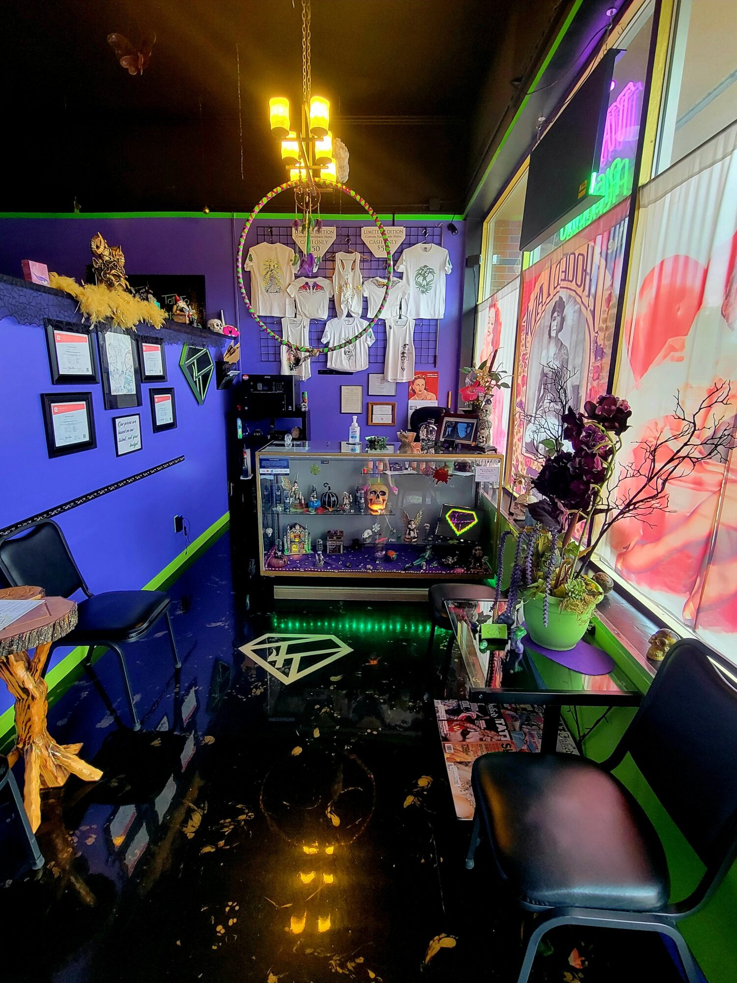 Interior of a colorful cafe with blue walls, a chandelier, display case, and seating area with plants and decorations.