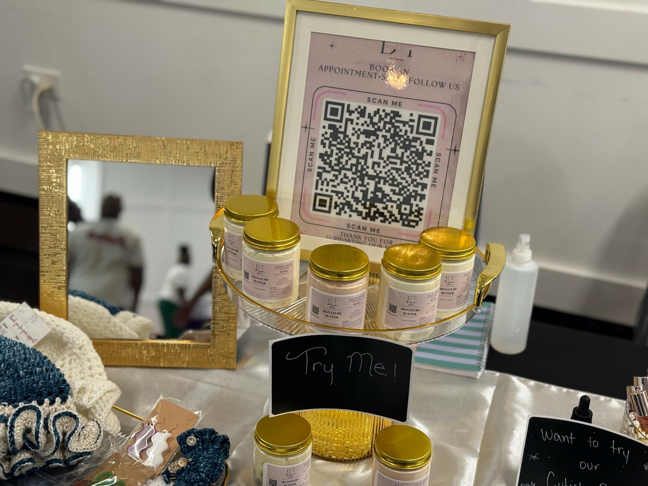 Display of jars, a framed QR code, a mirror, and a sign reading 'Try Me!' on a table.