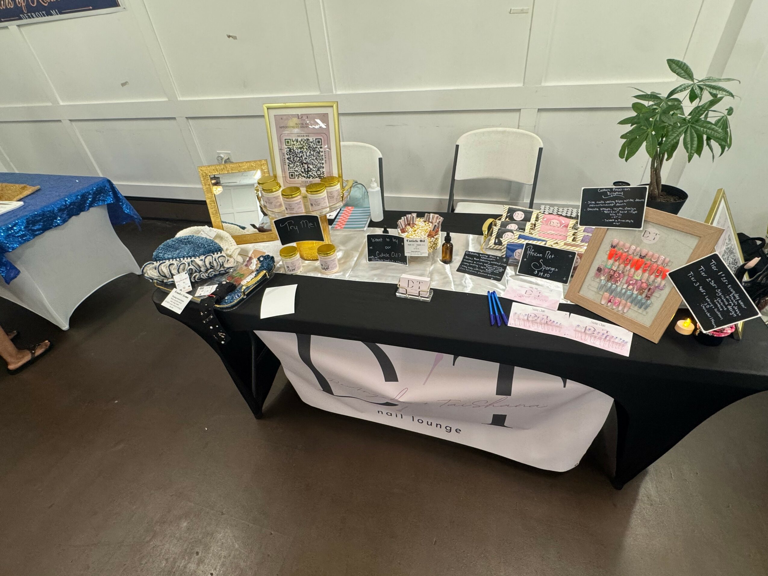 Table with framed photos, small items, and signs, set against a wall with a potted plant nearby.