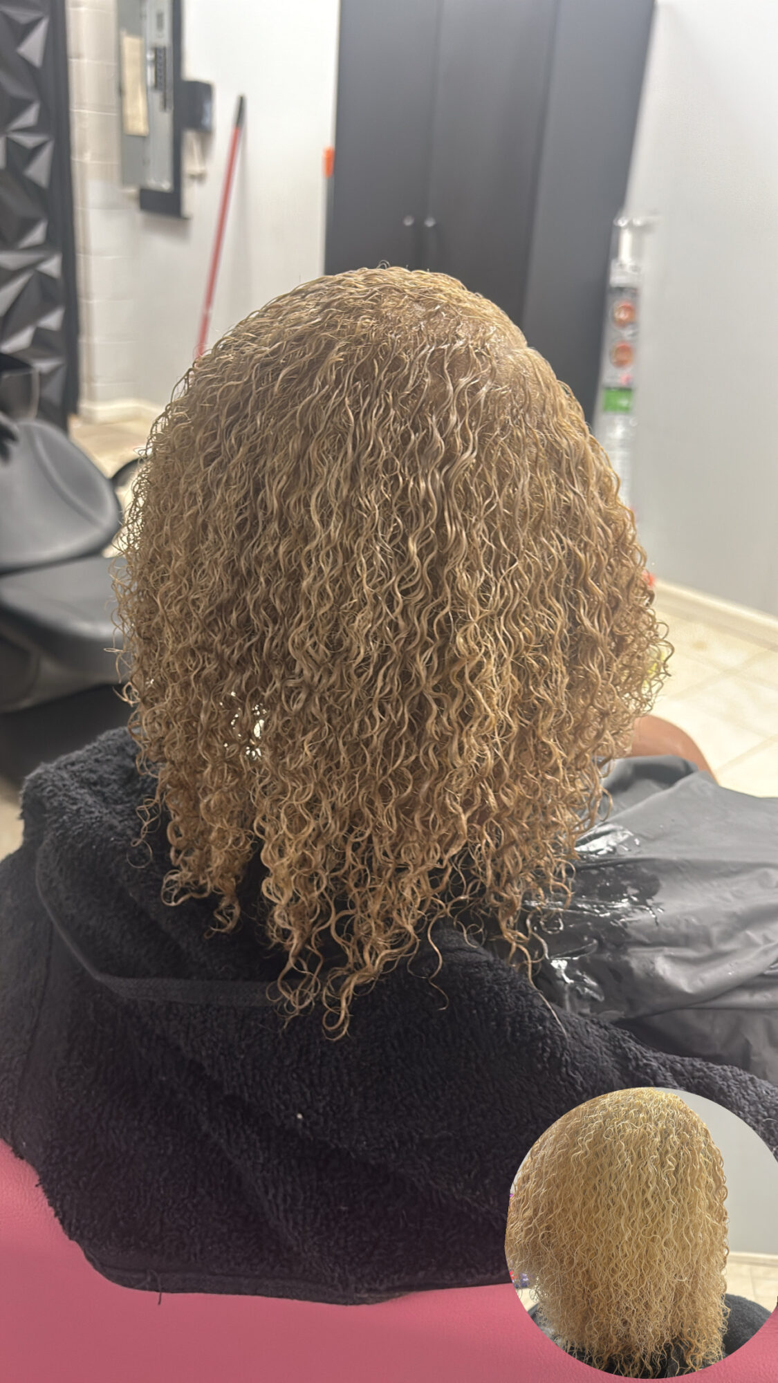 Back view of person with curly, blonde hair sitting in a salon chair, with a small inset showing the hair close-up.