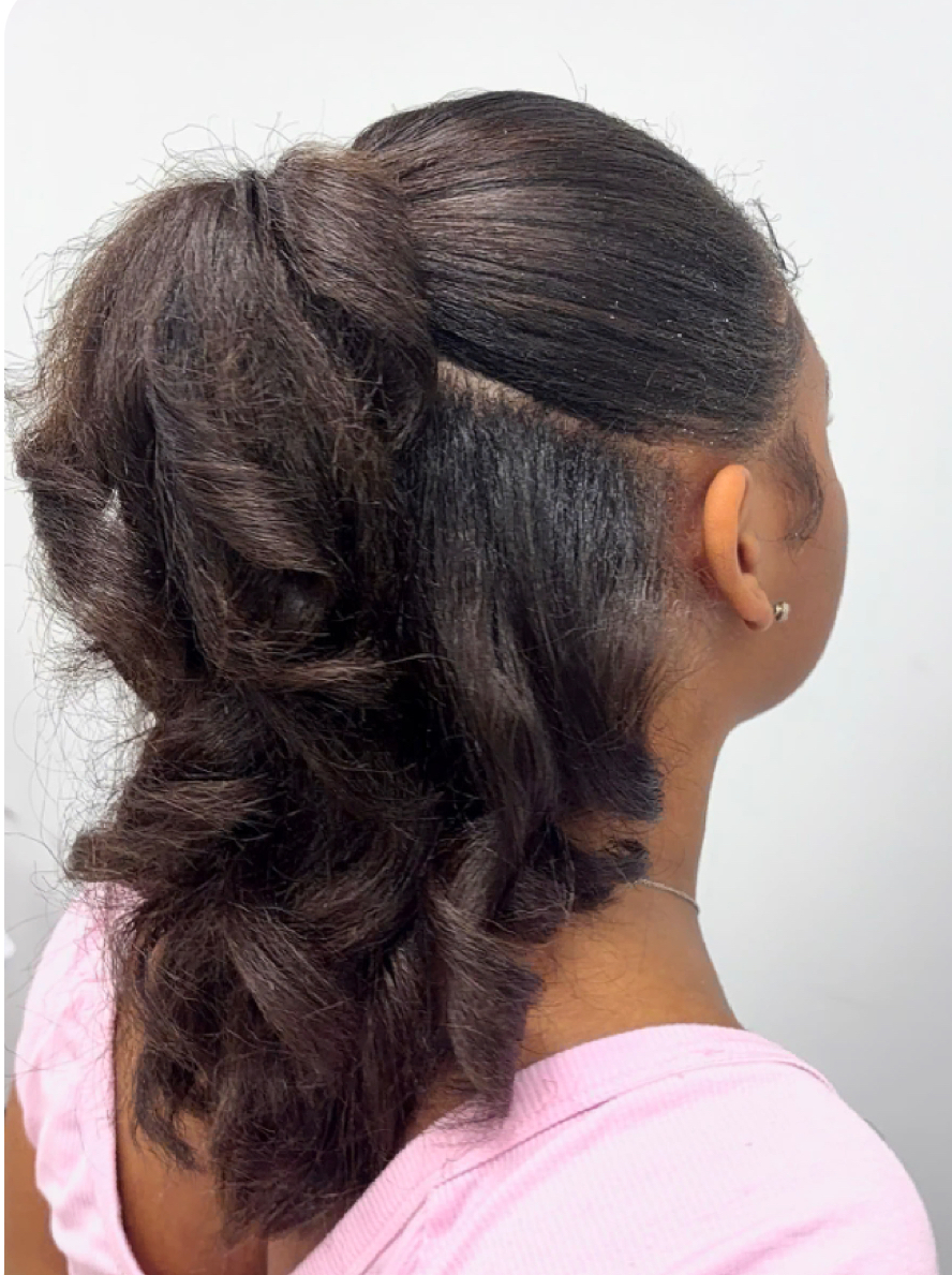 Side view of a woman with styled hair, wearing a pink top, against a plain background.